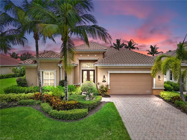 Mediterranean / spanish-style home featuring an attached garage, french doors, decorative driveway, stucco siding, and a front lawn