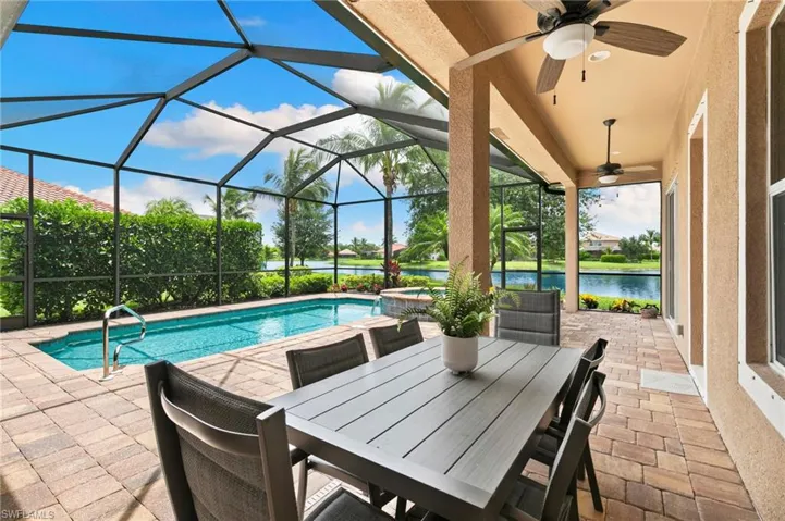 View of patio / terrace with ceiling fan, a water view, a pool with connected hot tub, and a lanai