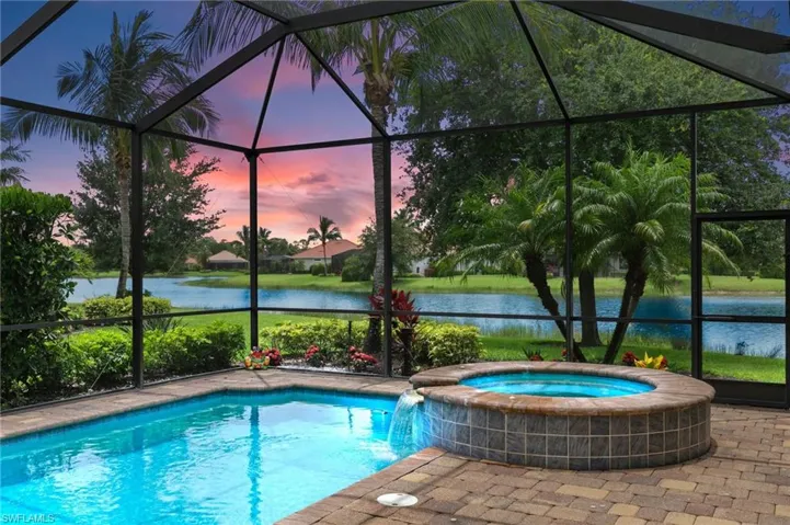 View of pool featuring a lanai, a water view, and a pool with connected hot tub