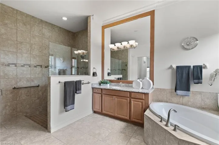 Bathroom with walk in shower, vanity, a bath, and tile patterned flooring