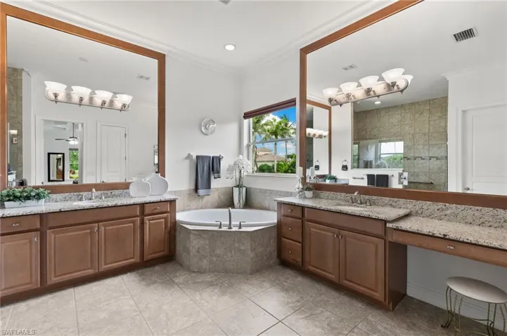 Full bathroom with two vanities, a bath, tile patterned flooring, crown molding, and a ceiling fan