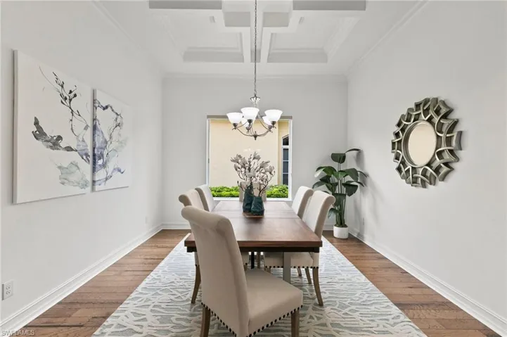 Dining room with coffered ceiling, a chandelier, dark wood finished floors, ornamental molding, and beam ceiling