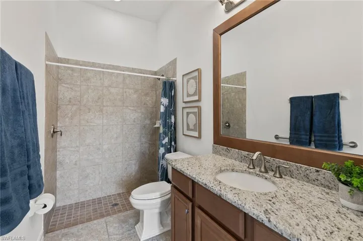 Bathroom with vanity, tiled shower, and tile patterned floors