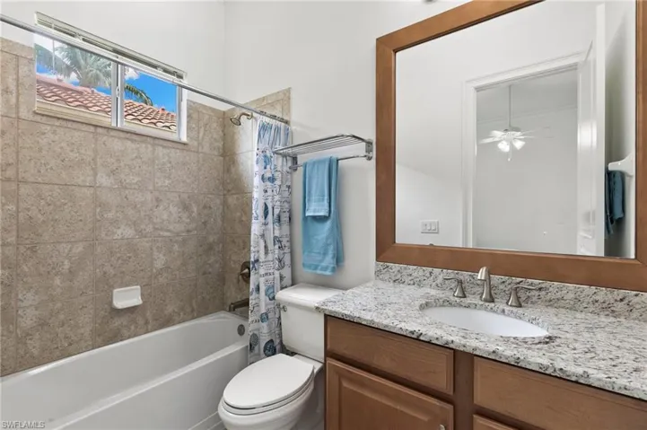 Full bathroom with vanity, shower / bath combination with curtain, and ceiling fan
