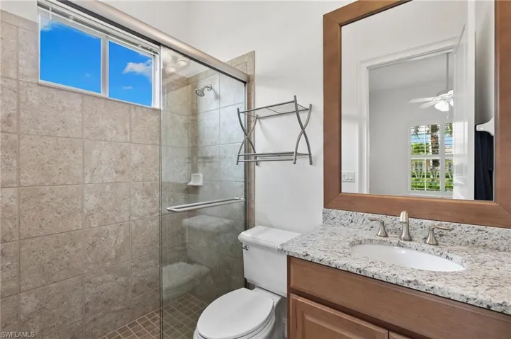 Full bathroom featuring vanity, a stall shower, and a ceiling fan