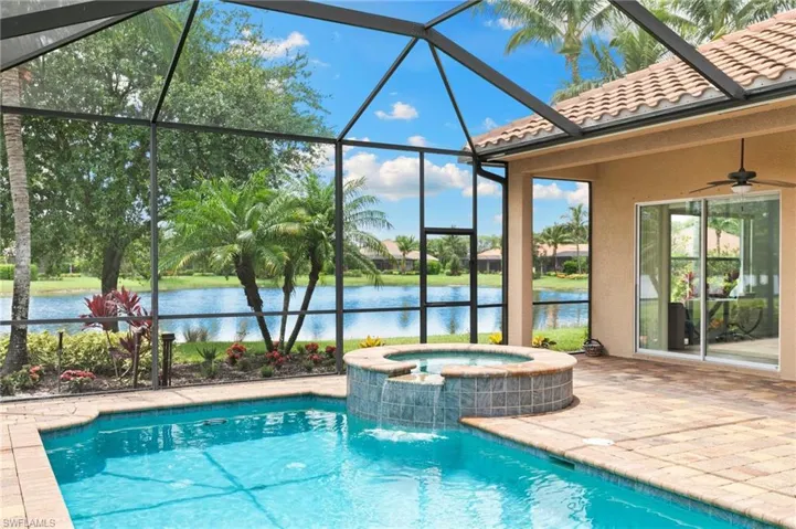 View of swimming pool featuring a water view, a patio, a pool with connected hot tub, and a lanai