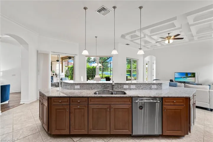 Kitchen with arched walkways, ceiling fan, dishwasher, open floor plan, and coffered ceiling