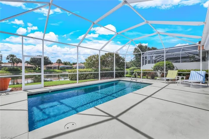 View of pool featuring glass enclosure, a water view, and a patio