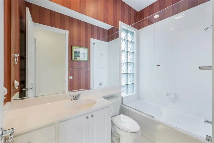 Full bathroom featuring vanity, a wealth of natural light, toilet, and bath / shower combo with glass door