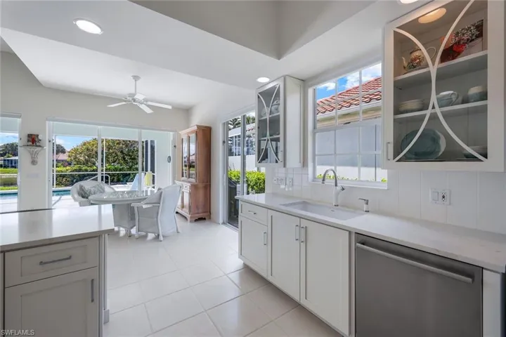 Kitchen featuring backsplash, ceiling fan, stainless steel dishwasher, sink, and light tile floors