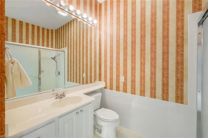 Bathroom with tile walls, vanity, and toilet