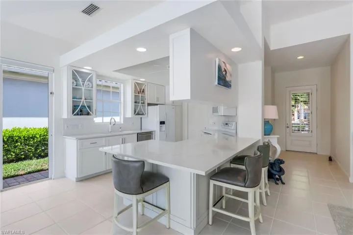 Kitchen with white fridge with ice dispenser, tasteful backsplash, kitchen peninsula, and light tile flooring