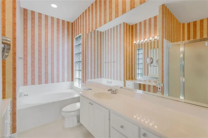 Bathroom featuring toilet, tile flooring, vanity, and a bath