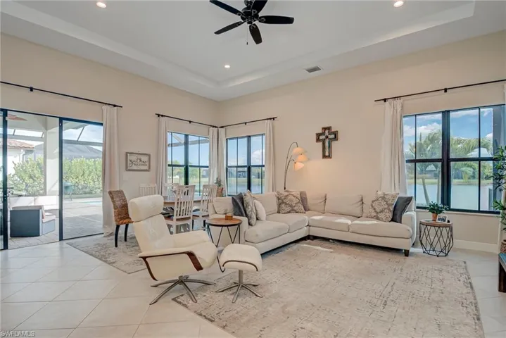 Living room featuring a ceiling fan, a tray ceiling, recessed lighting, and light tile patterned floors
