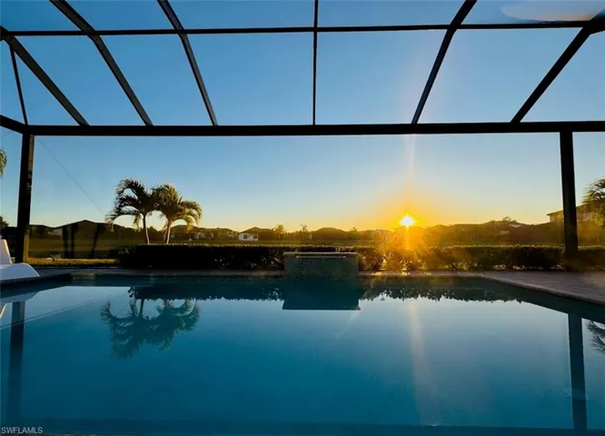 Pool at dusk featuring an outdoor pool, glass enclosure, and a sunroom