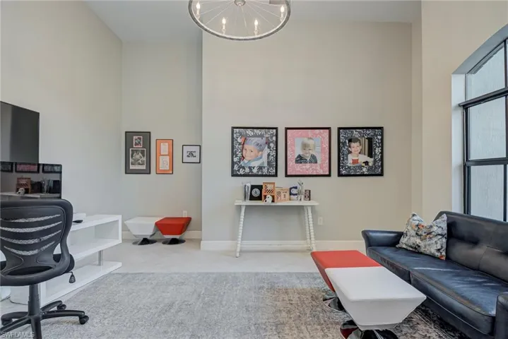 Office space featuring a high ceiling, hanging lights, and light carpet