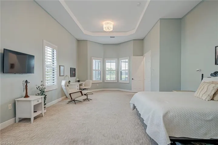 Primary bedroom featuring a tray ceiling and baseboards