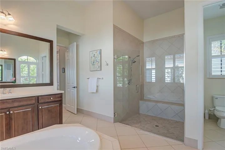 Primary bathroom with light tile patterned floors, a shower stall, vanity, and a garden tub