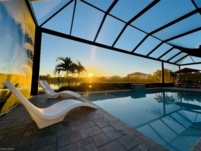 Pool at dusk with a lanai and an outdoor pool