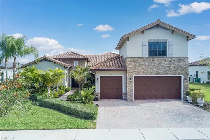 Mediterranean house, stucco siding, paver driveway, and stucco/stone siding