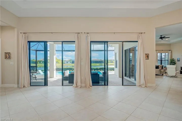 Great room featuring ceiling fan, a water view, light tile patterned floors, and a tray ceiling