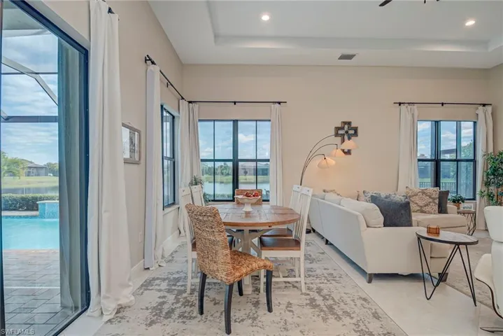 Dining area featuring a tray ceiling, recessed lighting, a water view, and a ceiling fan
