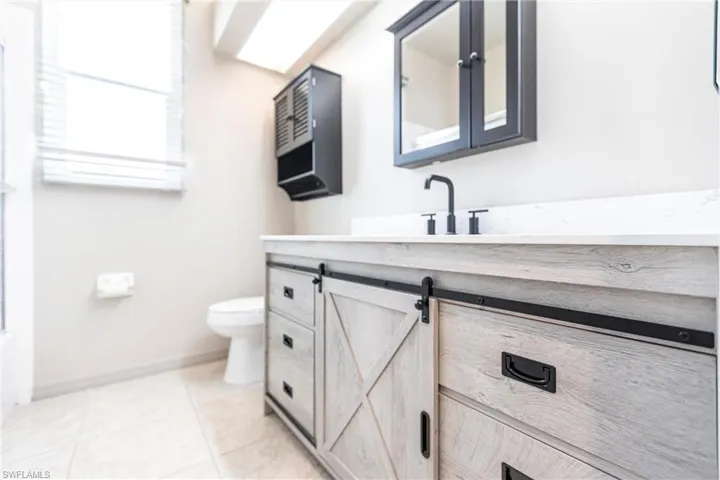 Bathroom featuring vanity, comfort height toilet, and tile patterned flooring with hurricane rated windows.