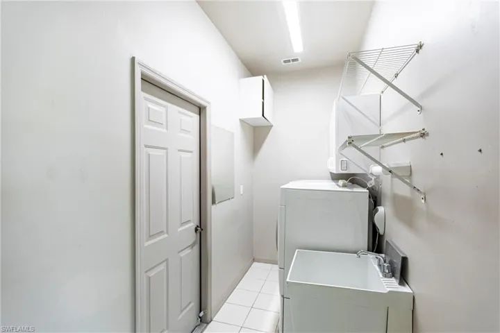 Washroom with technology (above) & storage cabinets, deep utility sink leading to garage.