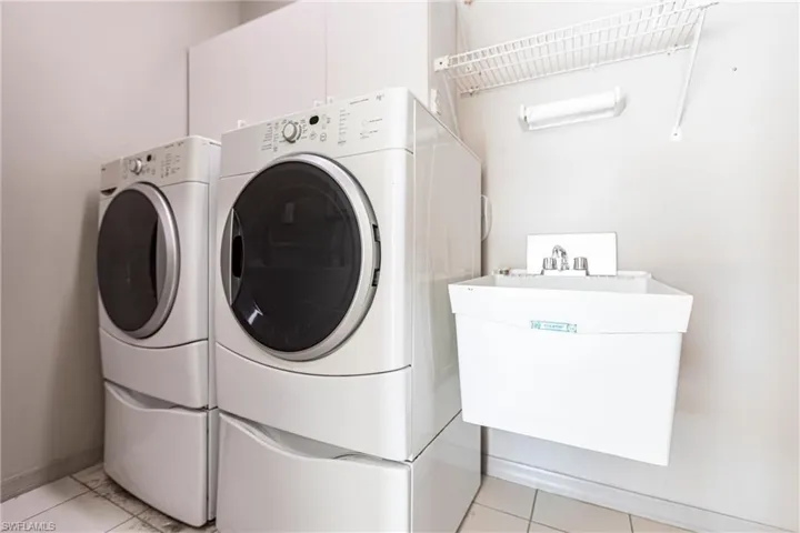 Laundry featuring front load washing machine and dryer and utility sink.