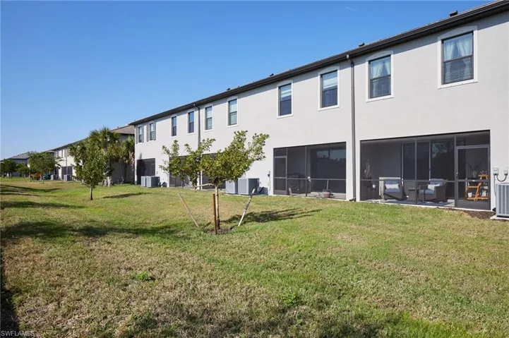 Rear view of property with central AC unit and a lawn