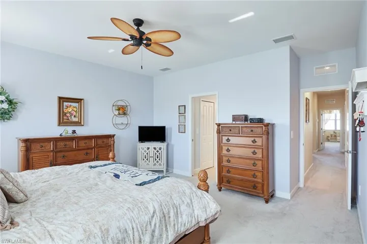 Bedroom with ceiling fan and light colored carpet