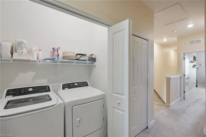 Laundry area featuring light carpet and independent washer and dryer