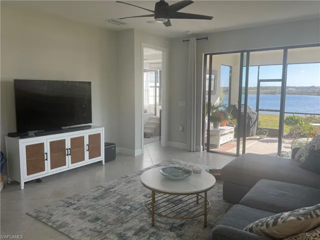 Living room featuring ceiling fan, a water view, and light tile patterned flooring