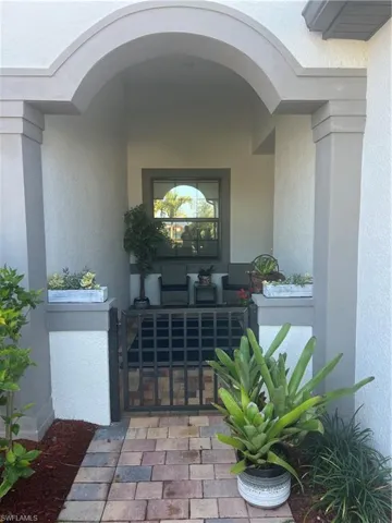 View of exterior entry featuring a gate and stucco siding
