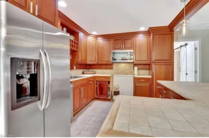 Kitchen with decorative light fixtures, backsplash, recessed lighting, a barn door, and appliances with stainless steel finishes