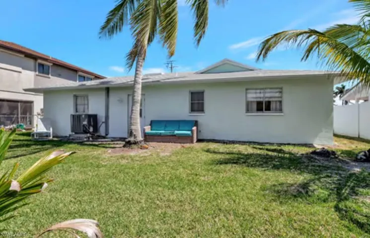 Rear view of property with stucco siding, cooling unit, a lawn, and fence