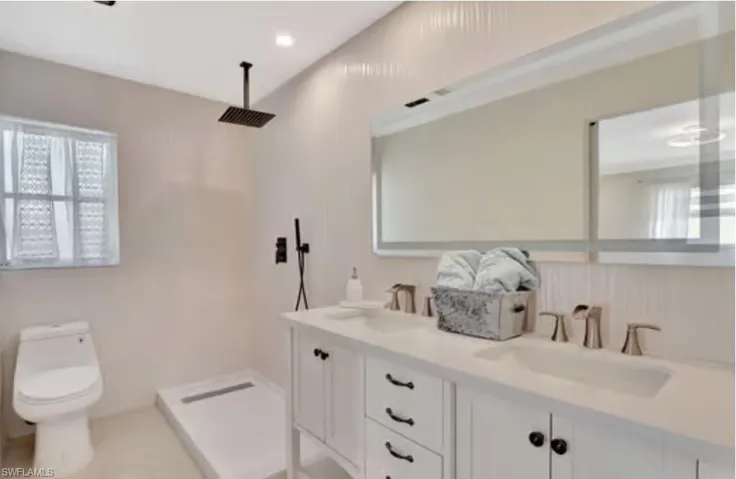 Bathroom with walk in shower, toilet, double vanity, and a sink