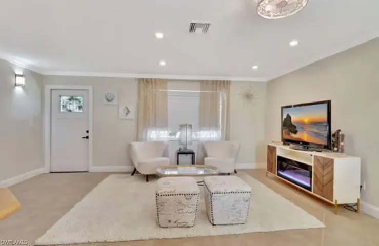 Living room with visible vents, baseboards, light colored carpet, ornamental molding, and recessed lighting
