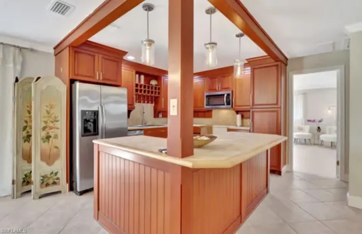 Kitchen featuring visible vents, light tile patterned flooring, stainless steel appliances, light countertops, and pendant lighting