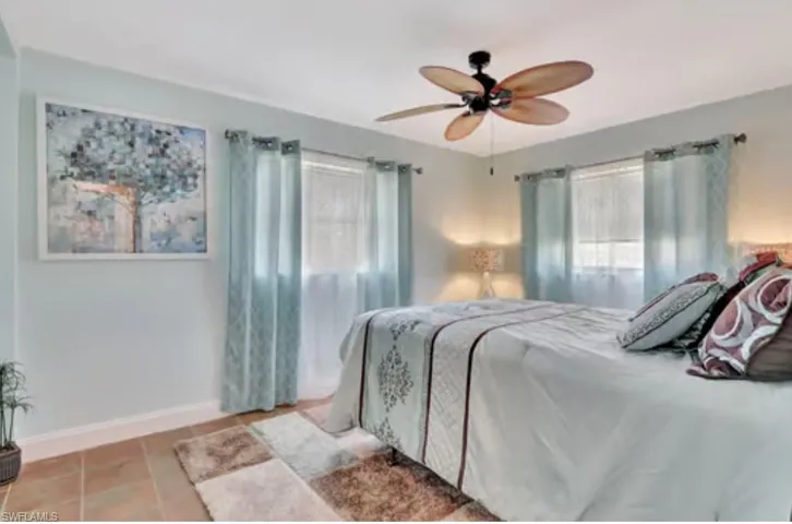 Bedroom with tile patterned flooring, multiple windows, a ceiling fan, and baseboards