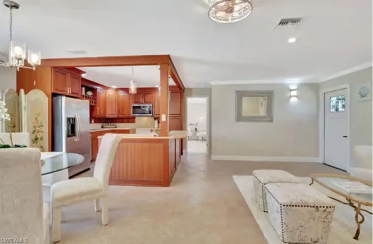 Kitchen featuring visible vents, crown molding, open floor plan, an inviting chandelier, and stainless steel appliances