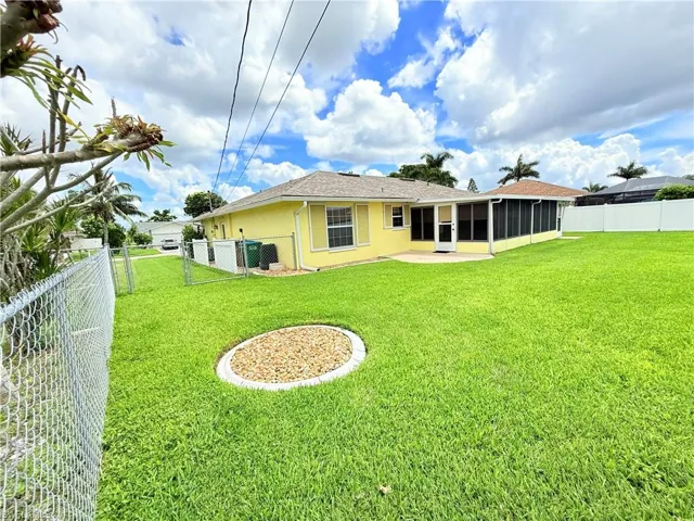 Rear view of house with a fenced backyard, stucco siding, a sunroom, a gate, and a patio