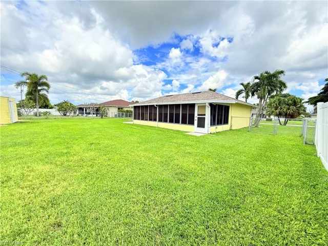 Rear view of house featuring a fenced backyard and a sunroom