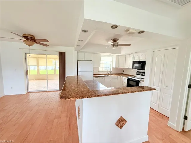 Kitchen featuring white appliances, light wood-style floors, white cabinets, and a ceiling fan