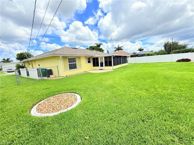 Back of house featuring a fenced backyard, a sunroom, stucco siding, roof with shingles, and a gate