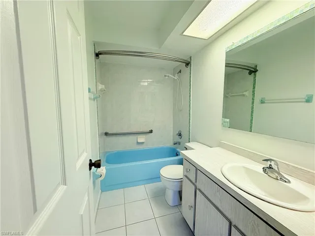 Bathroom featuring vanity, tub / shower combination, and light tile patterned flooring