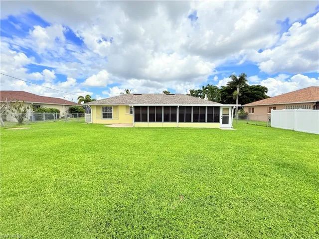Rear view of property with a fenced backyard and a sunroom