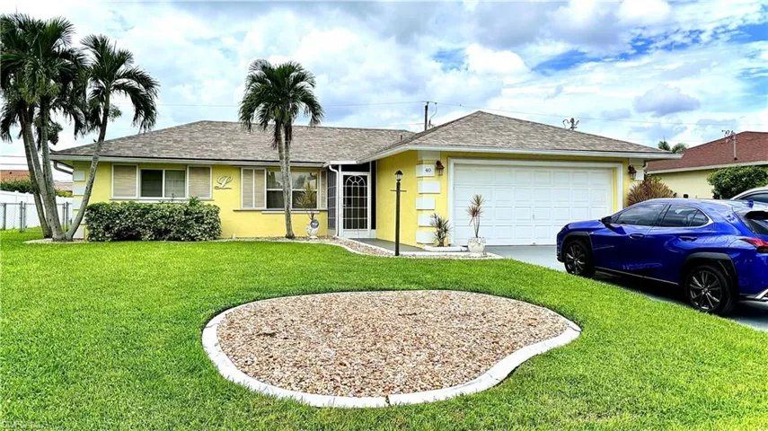 Ranch-style house with stucco siding, roof with shingles, and a front lawn