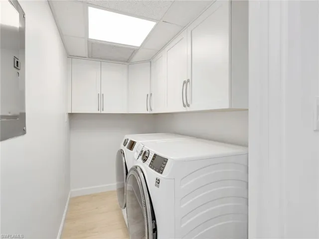 In Unit Laundry room featuring a drop ceiling, cabinet space, washing machine and clothes dryer.