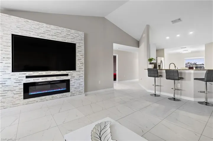 Living room with lofted ceiling, marble finish floors, and baseboards